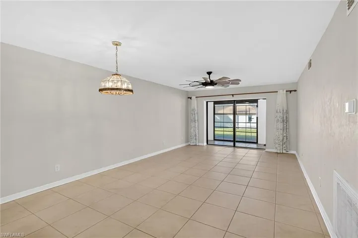 Empty room featuring light tile patterned floors, a ceiling fan, and a chandelier