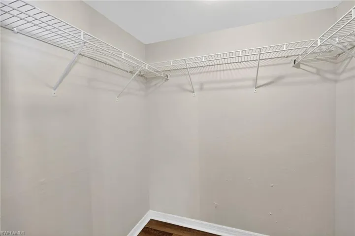 Walk in closet with dark wood-type flooring