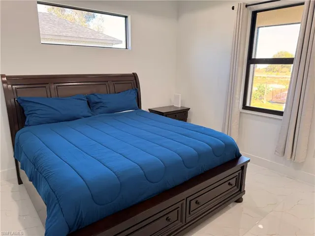 Bedroom with light marble finish flooring and multiple windows