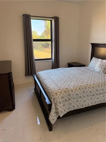 Bedroom featuring light marble finish flooring and baseboards