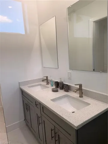 Full bath with double vanity and light marble finish floors