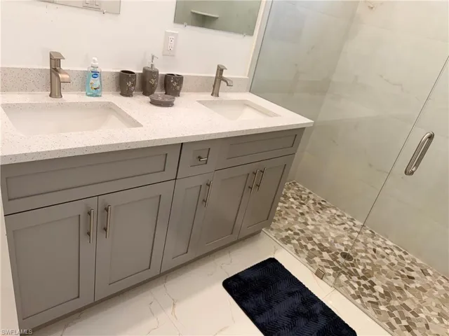 Full bath featuring double vanity and a shower stall