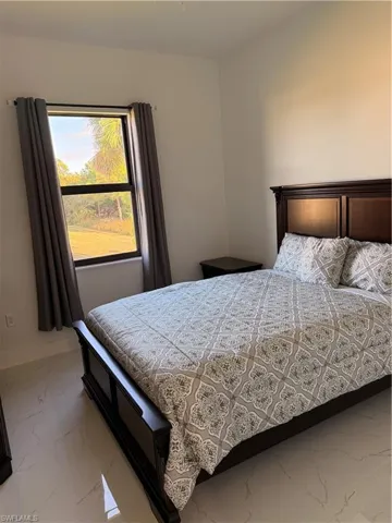 Bedroom featuring light marble finish floors and baseboards