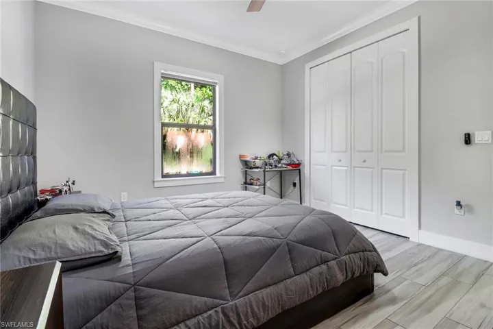 Bedroom featuring light hardwood / wood-style flooring, a closet, ceiling fan, and crown molding