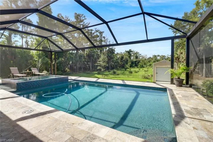 View of pool featuring a storage shed, a patio, and glass enclosure
