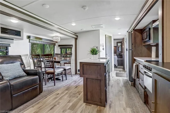 Kitchen with stainless steel microwave, a kitchen island, and light wood-type flooring