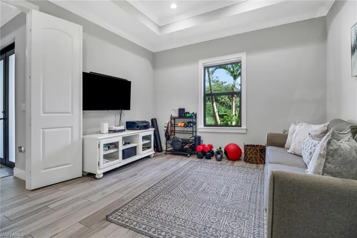 Living room featuring crown molding, a raised ceiling, and light hardwood / wood-style flooring
