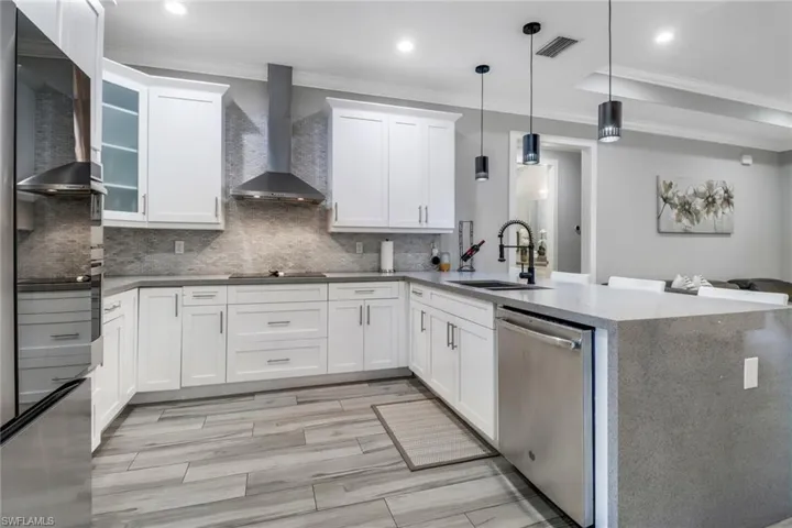Kitchen featuring sink, stainless steel dishwasher, white cabinets, and wall chimney exhaust hood