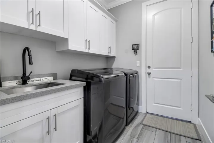 Washroom featuring washer and clothes dryer, sink, crown molding, and cabinets
