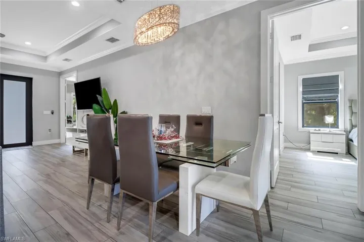 Dining space with an inviting chandelier, light hardwood / wood-style floors, crown molding, and a tray ceiling