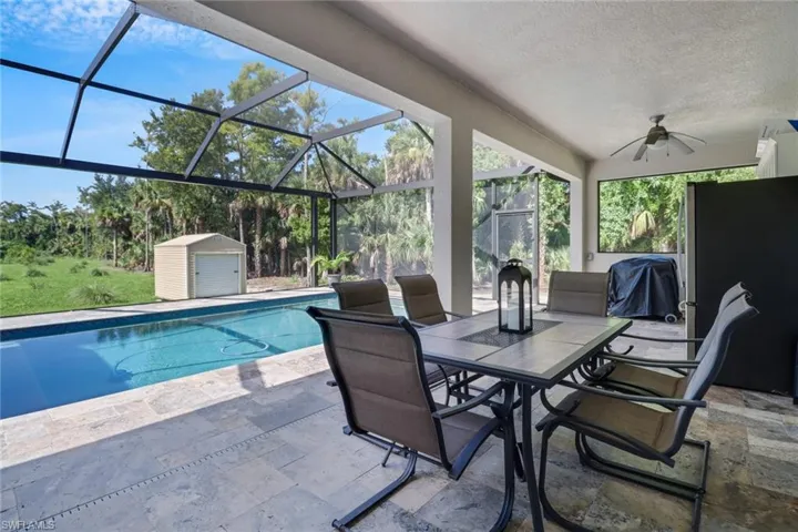 View of pool with a patio, ceiling fan, a storage unit, and a lanai