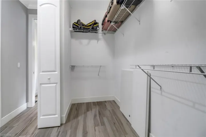 Walk in closet with light hardwood / wood-style flooring