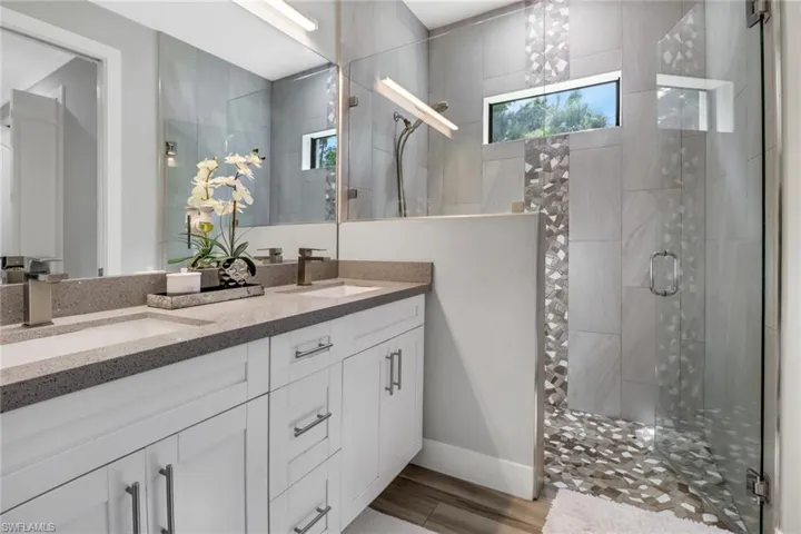 Bathroom featuring double vanity and an enclosed shower