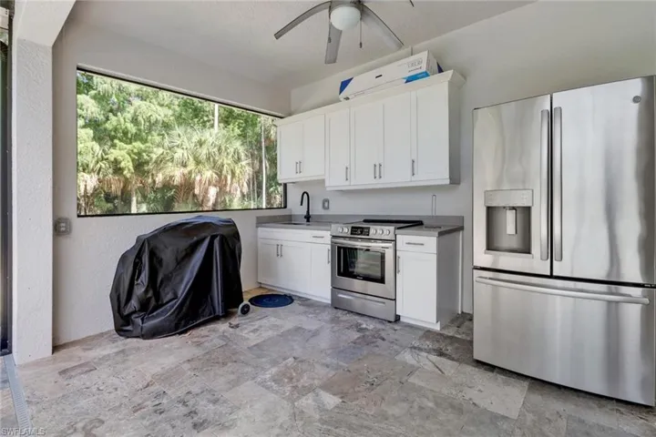 Kitchen featuring light tile patterned flooring, white cabinets, ceiling fan, appliances with stainless steel finishes, and sink