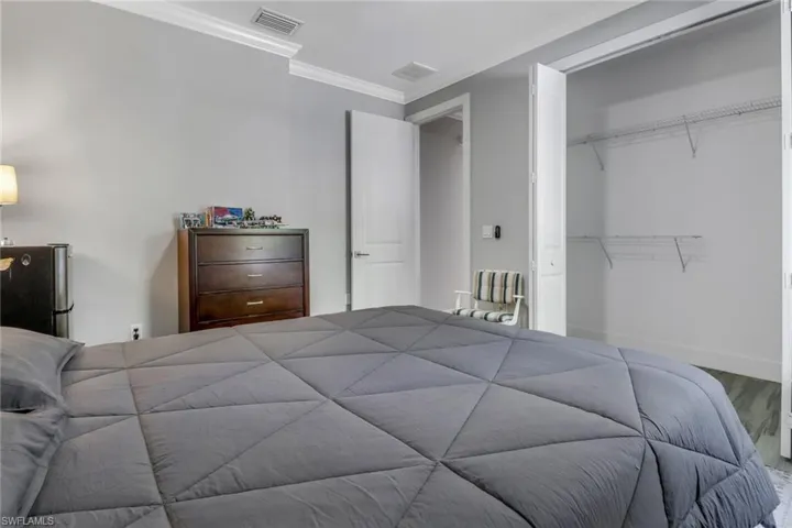 Bedroom with hardwood / wood-style floors, a closet, stainless steel fridge, and ornamental molding