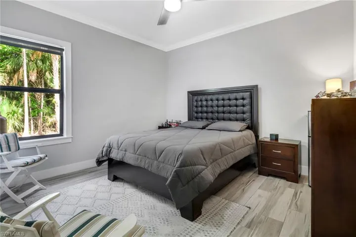 Bedroom with ornamental molding, ceiling fan, and light wood-type flooring
