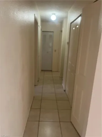 Hall featuring light tile patterned flooring and baseboards