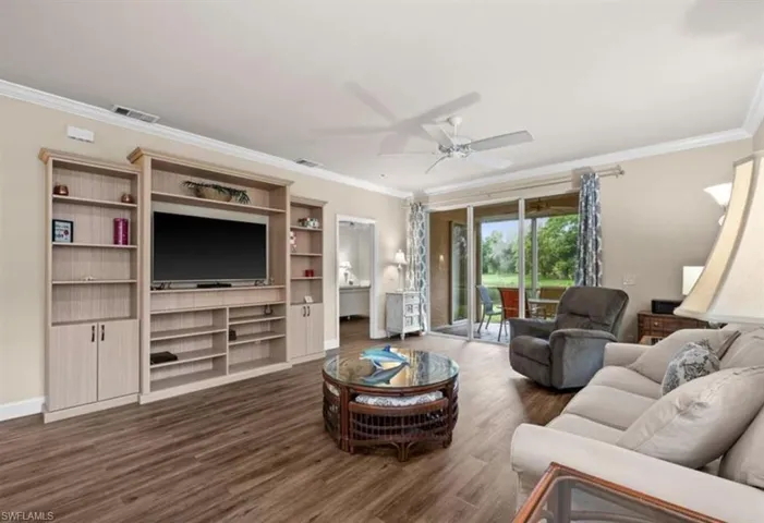 Living room with ceiling fan, dark hardwood / wood-style flooring, and crown molding