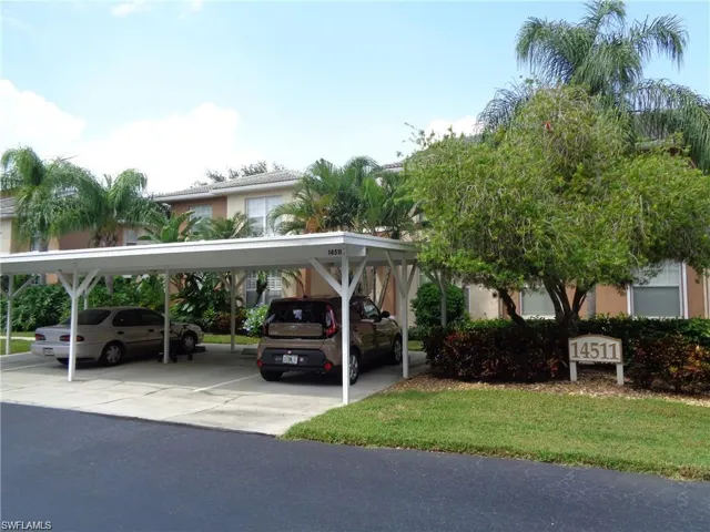 View of car parking featuring a lawn and a carport