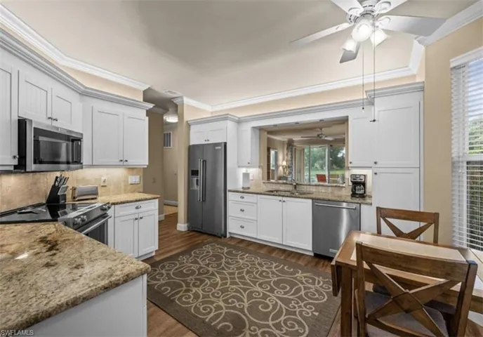 Kitchen featuring dark hardwood / wood-style floors, ceiling fan, tasteful backsplash, high quality appliances, and ornamental molding
