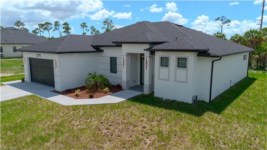 View of front of property with a front lawn, a garage, driveway, stucco siding, and roof with shingles