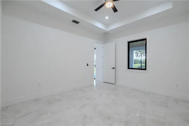 Empty room featuring a tray ceiling and a ceiling fan