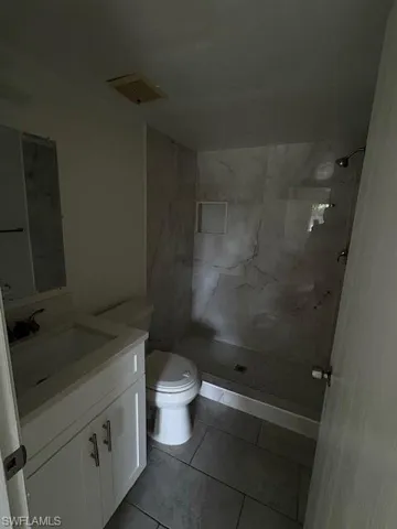 Bathroom with vanity, walk in shower, and tile patterned flooring