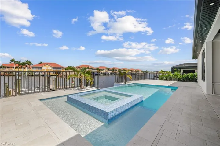 View of pool with a water view, a patio, a pool with connected hot tub, and a residential view