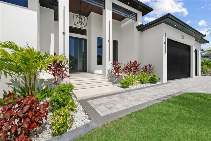 Entrance to property featuring a garage, stucco siding, french doors, and decorative driveway