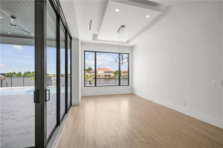 Unfurnished room with wood finished floors, recessed lighting, a water view, and a raised ceiling