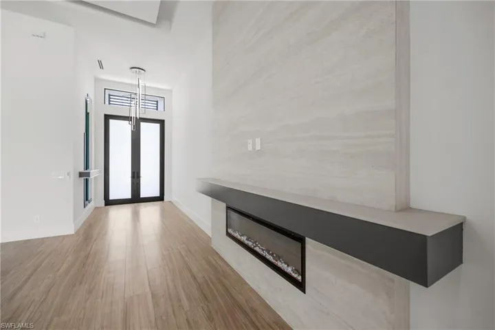 Foyer entrance with wood finished floors, french doors, and a glass covered fireplace