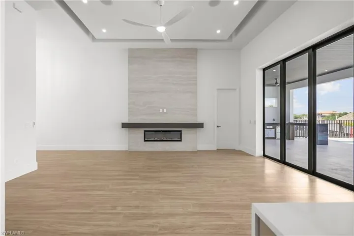 Unfurnished living room with light wood-type flooring, recessed lighting, a tile fireplace, and ceiling fan