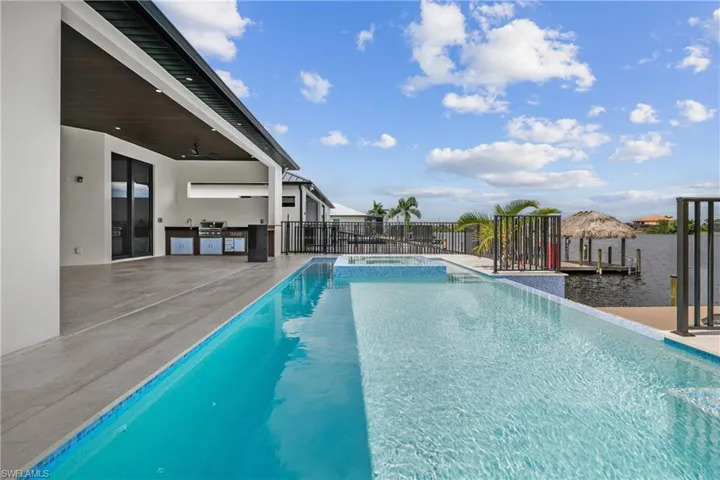 View of swimming pool featuring a pool with connected hot tub, ceiling fan, a patio, and exterior kitchen