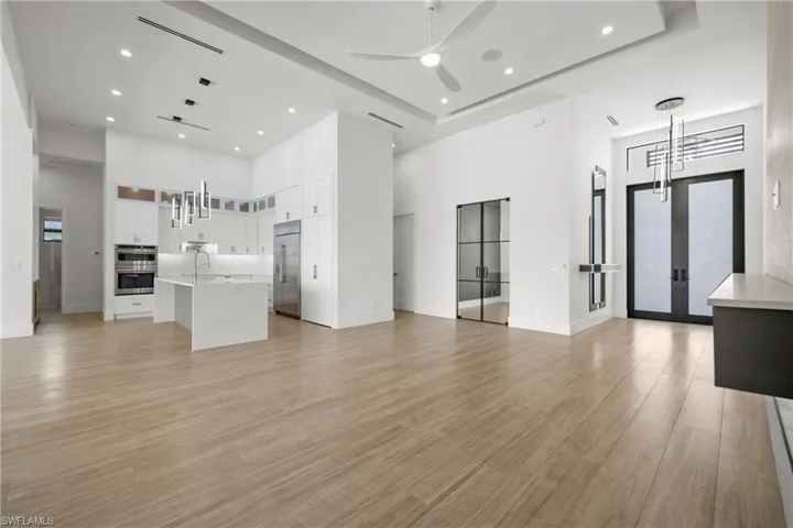 Unfurnished living room featuring light wood-style flooring, french doors, a high ceiling, recessed lighting, and a ceiling fan