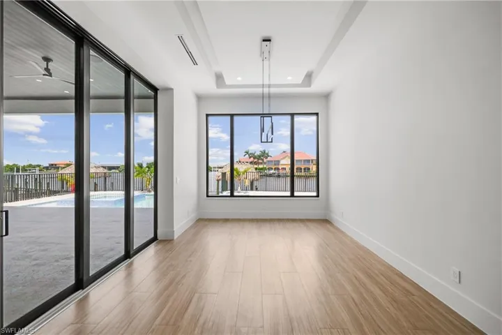 Empty room featuring wood finished floors, ceiling fan, recessed lighting, and a tray ceiling