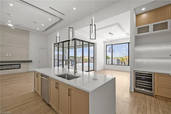 Kitchen with wine cooler, a fireplace, light wood-type flooring, open floor plan, and recessed lighting
