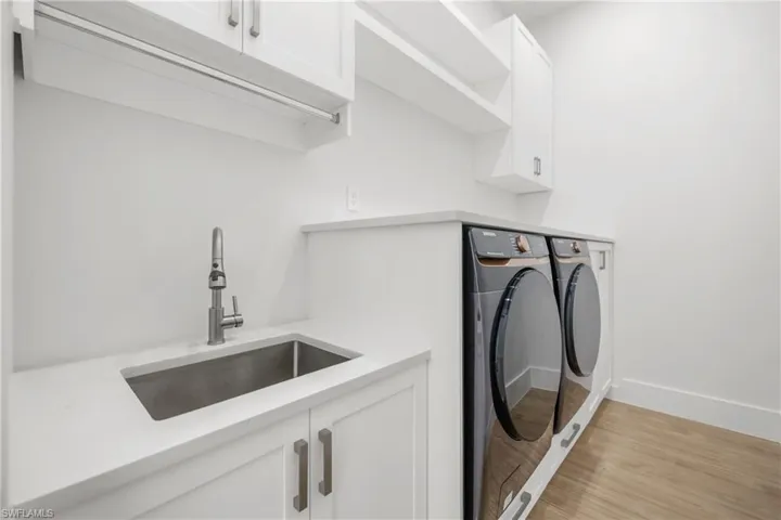 Laundry room with washer and clothes dryer, cabinet space, and light wood-type flooring