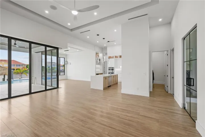 Unfurnished living room featuring a ceiling fan, light wood-type flooring, recessed lighting, and a high ceiling