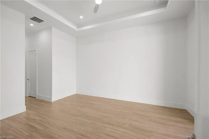 Spare room featuring recessed lighting, light wood-style floors, a raised ceiling, and a ceiling fan