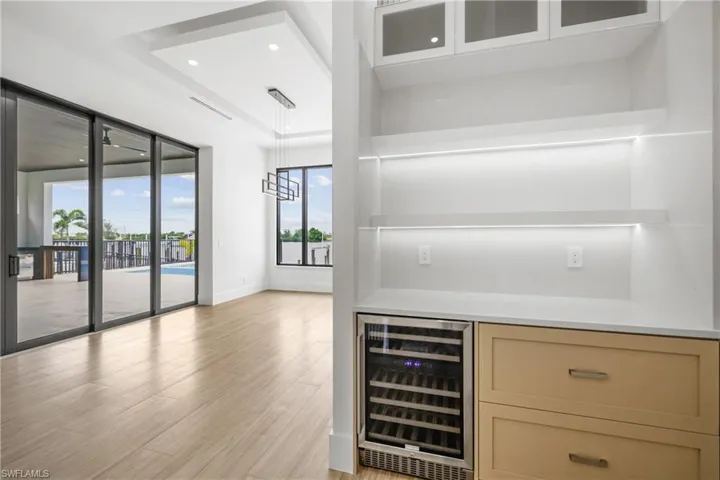 Bar with beverage cooler, light wood finished floors, recessed lighting, and pendant lighting