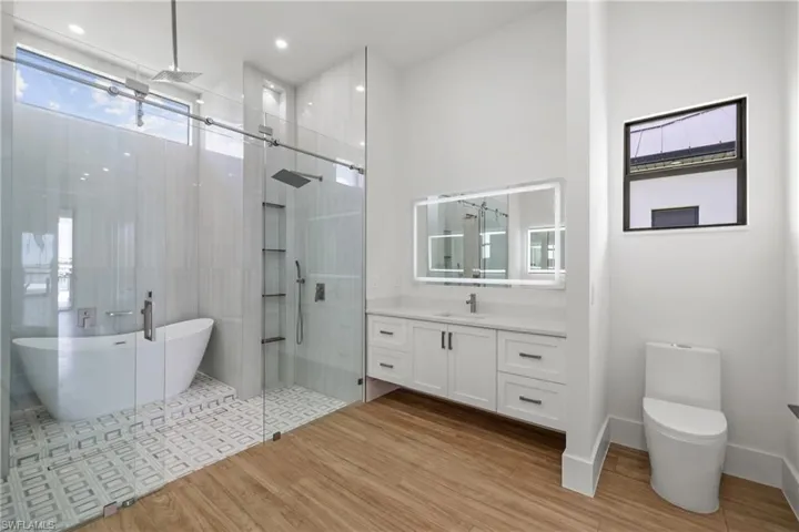 Full bathroom featuring a stall shower, a freestanding tub, vanity, and wood finished floors