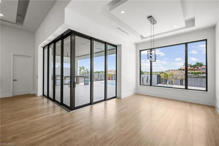 Empty room with a raised ceiling, light wood finished floors, recessed lighting, and a water view