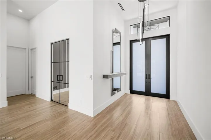 Foyer featuring a high ceiling, french doors, and wood finished floors