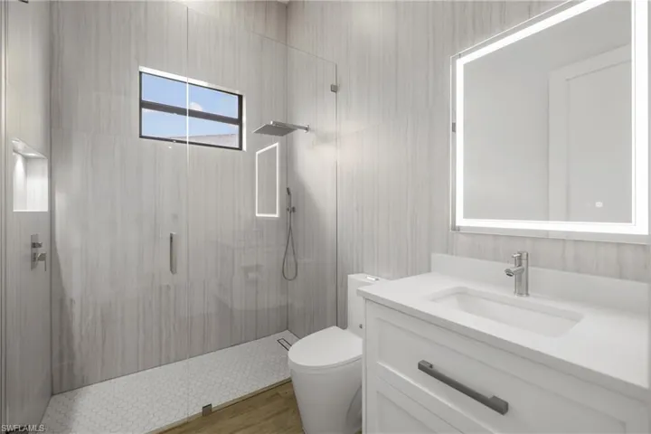Full bath with a stall shower, vanity, and wood finished floors