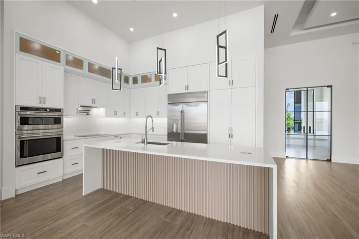 Kitchen with a high ceiling, recessed lighting, light wood-style flooring, a kitchen island with sink, and light countertops