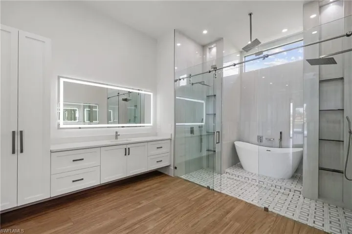 Full bathroom with a stall shower, vanity, a soaking tub, and wood finished floors