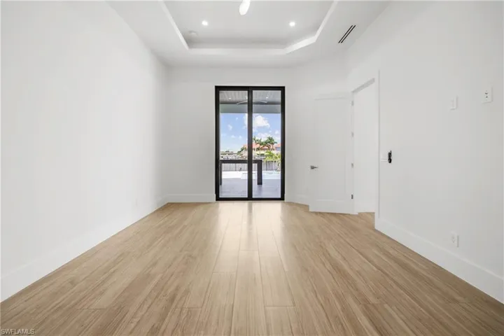 Unfurnished room featuring light wood finished floors, recessed lighting, and a tray ceiling