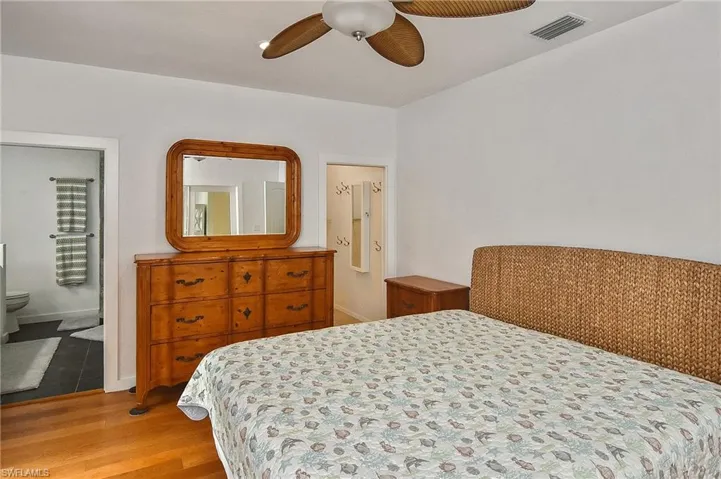 Bedroom with ceiling fan, connected bathroom, and light hardwood / wood-style flooring