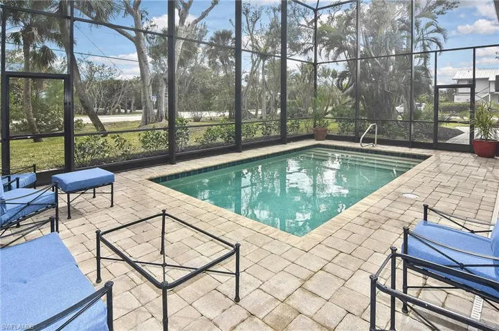 View of pool featuring glass enclosure and a patio