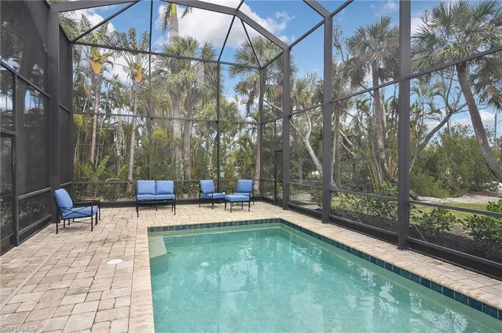 View of pool with glass enclosure and a patio